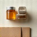Eco-friendly packaging materials such as corrugated cardboard, recycled paper, and a small glass jar, artistically arranged on a light background to convey sustainable packaging solutions.